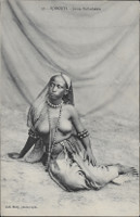 Na ernobl pohlednici je mlad domorod ena s odhalenou horn
            st tla. M na sob dlouhou sukni, korle kolem krku, dlouh korle
            a nramky. Na hlav m dlouh tek.