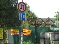 Na zbru fotografie z vletu je v pozad star ocelov eleznin most pes Vltavu. Ped nm je zsti zelenou plachtou pokryt plot, rozvade 
          na elektinu a na plot a dvech luto erven cedule. Na obrzku jsou dopravn znaky. Most je z 19. stolet a je na trati z eskch Budjovic na 
          esk Krumlov a dle na umavu.