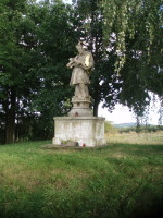 Na fotografii je na travnat vyvenin dobe osvtlen 
          socha. Je vidt zdn i kamenn podstavec.