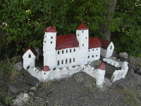Na tto fotografii jsou vidt vechny budovy miniatury hradu. Jsou to dv ve, dva palce, dv men budovy, dv mal viky 
          a hradby. Vechny zdi jsou bl, stechy jsou erven a okna ern.