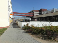 Na fotografii z vletu jsou budovy spojen nadzemnm ervenm, krytm prosklenm
          tubusem na pechzen. Budova nalevo je bl. Budova napravo je ed s ervenmi stechami.