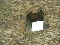 Na fotografii je st zdi s gotickm ostnm okna palce. V kamenech ostn po stranch a dole jsou otvory.