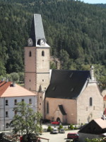 Na fotografii je od hradu v a lo kostela a dm na nbe. 
          Dle je vidt zalesnn protj svah.