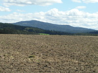 Na fotografii je vidt erstv obdlan pole, les a kopce.