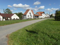Na fotografii je vidt silnice prochzejc zatravnnou plochou.
          Domy jsou na severn stran vchodn sti nvsi.