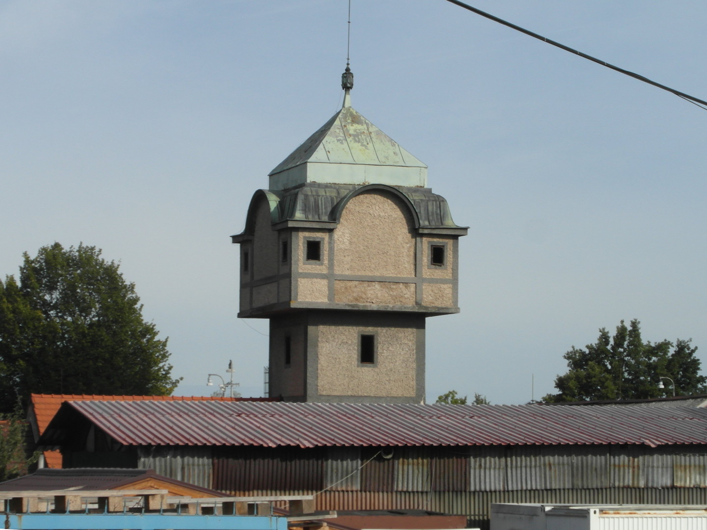 Na zbru fotografie z vletu je stecha a st budovy z vlnitho plechu. Za n vynv v o tvercovm pdorysu. Jej horn trochu 
  ozdobn st m vt plochu pdorysu, ne zbytek ve a m zelenou stechu. Na vi jsou obdlnkov oknka. Jedn se nejspe o vodojem,
  mon ji bval. Mohla by to bt technick pamtka. Vodojem je vidt detailnji.