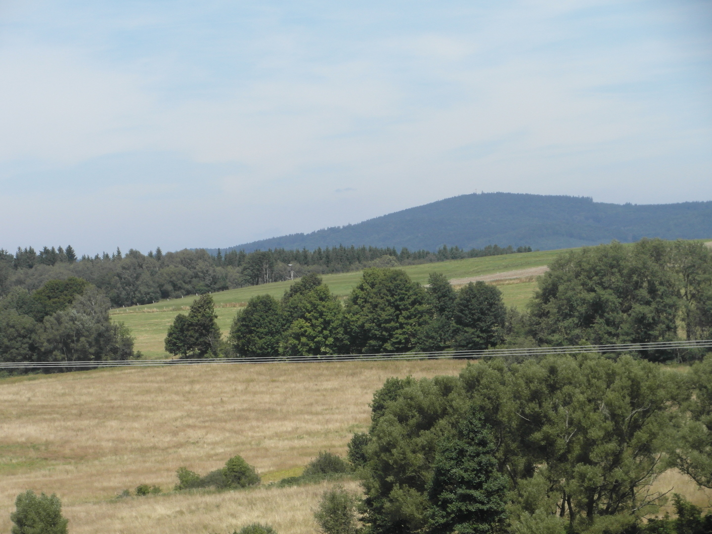 Na fotografii z vletu jsou 
  pole, louky, lesy a kopec. Jsou vidt tak drty vysokho napt.