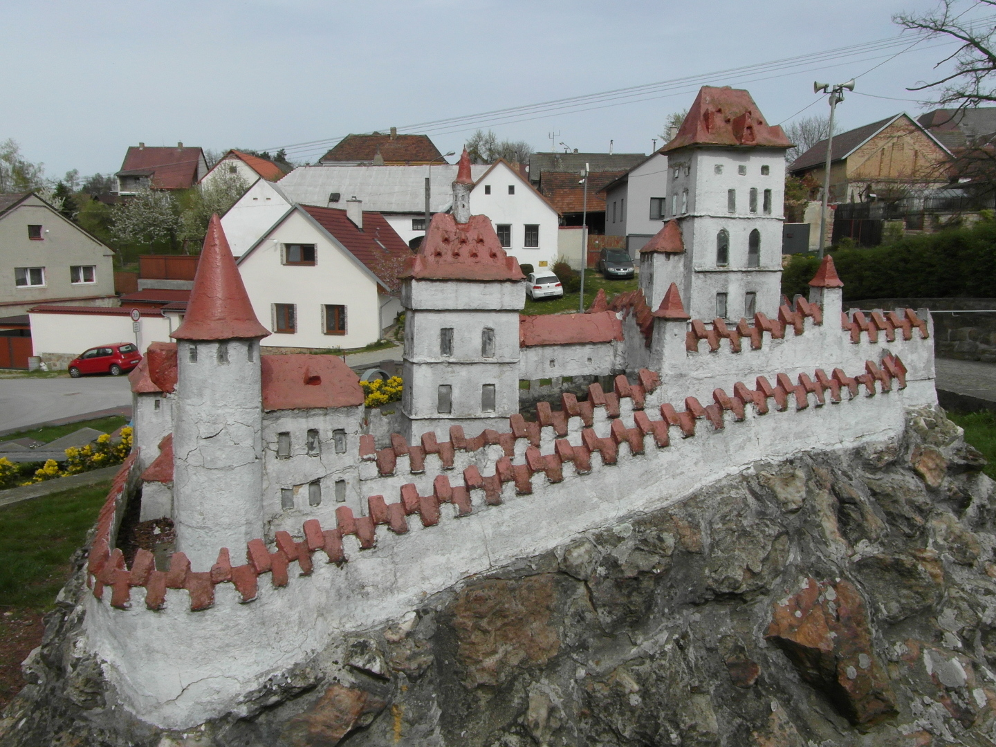 Miniatura Karltejna se nachz na svahu na skalce tho pdorysu, kter piblin odpovd pdorysu skutenho hradu. Stny hradu jsou
  bl a stechy erven. Pod miniaturou je minigolfov hit. Karltejn je od vchodu. Sv. K, Nanebevzet Panny Marie a Csask palc.