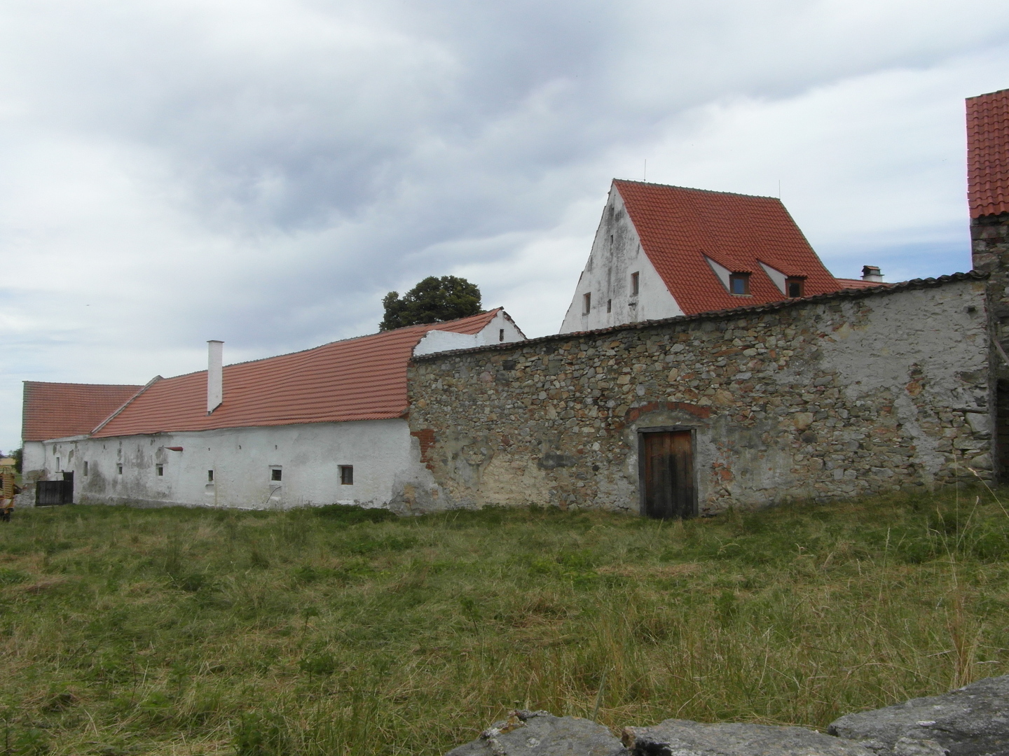 Na fotografii je vidt ze hospodsk budovy a jenom mal st pcharu. 
  Za zd vynv tt a stecha obytn budovy. Hospodsk staven a obytn budova 
  jsou obarveny na blo. Ve zdi jsou devn vrata na mst pvodnch vtch.
  Vechna staven maj prejzov stechy. Ve stee obytn budovy jsou nov udlna
  okna pdnch vestaveb. Tm je naruena historick autenticita tvrze.